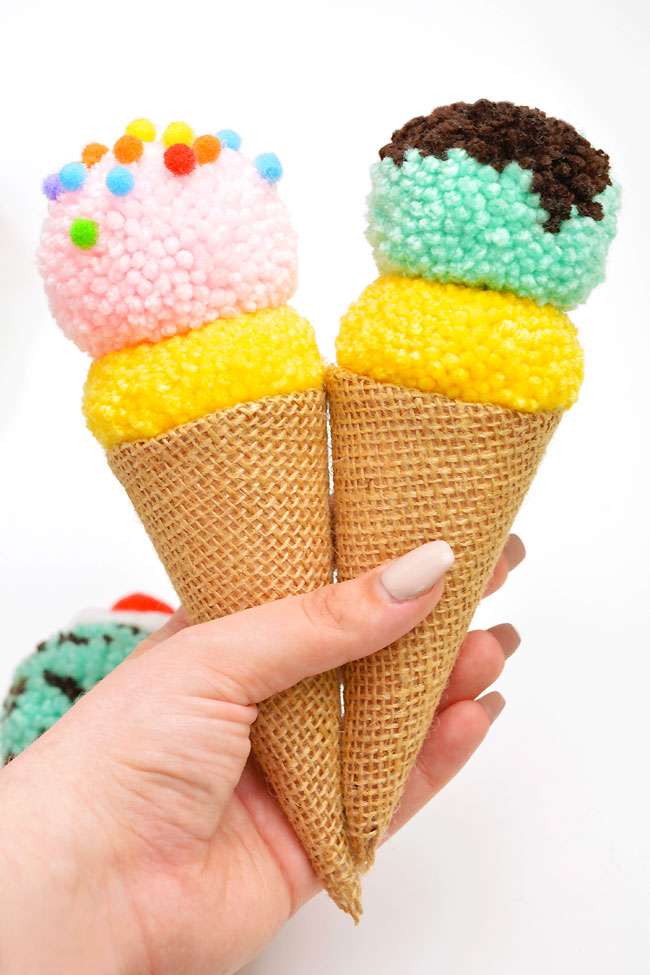 Holding two colourful pom pom ice cream crafts