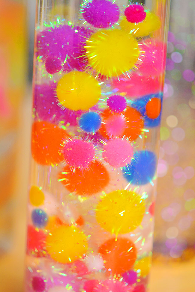 Closeup on a DIY sensory bottle with glittery pom poms