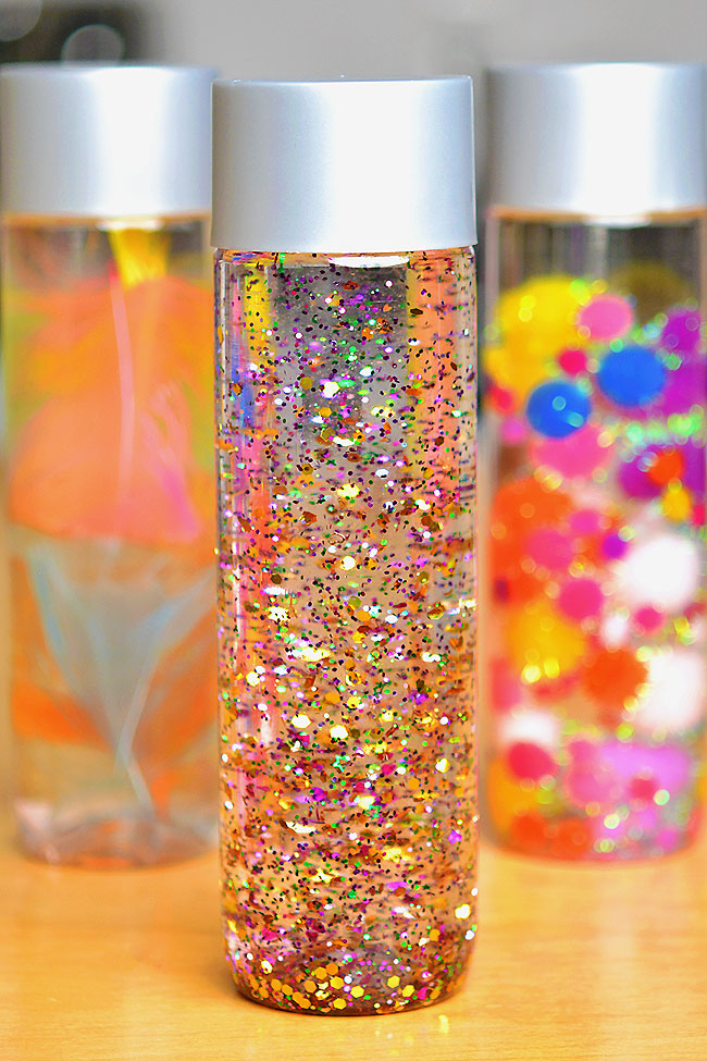 Sensory bottles filled with glitter, feathers, and pom poms