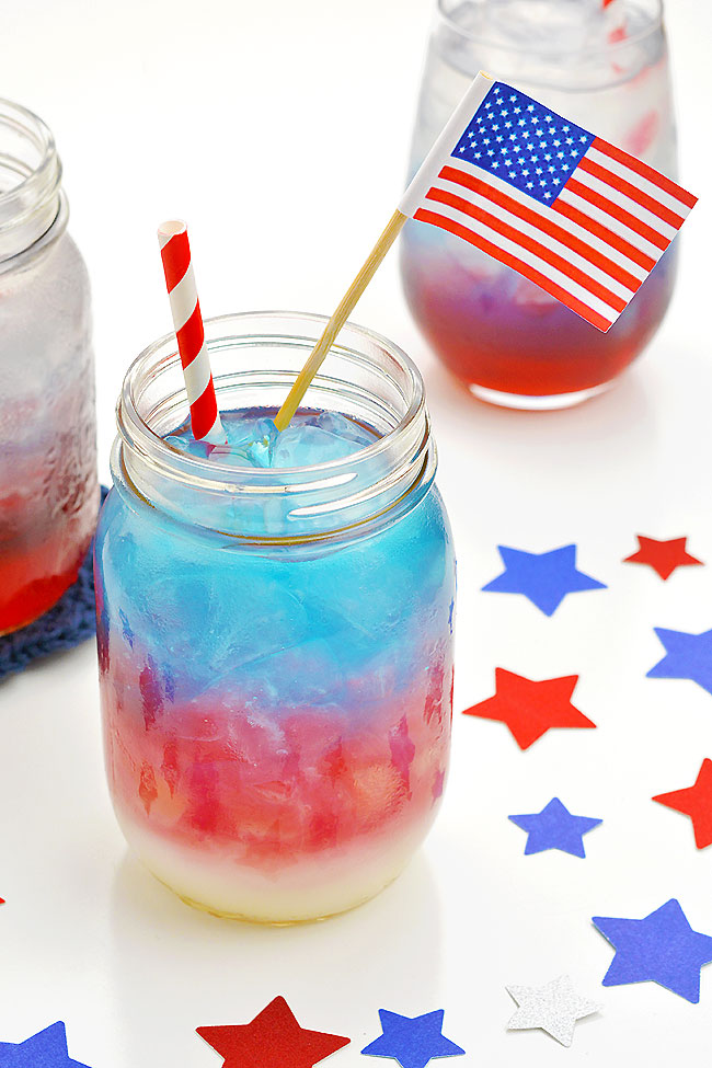Red white and blue 4th of July layered drink garnished with a straw and an American flag