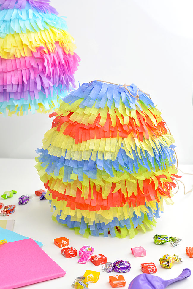 Paper mache pinatas surrounded by tissue paper and candy