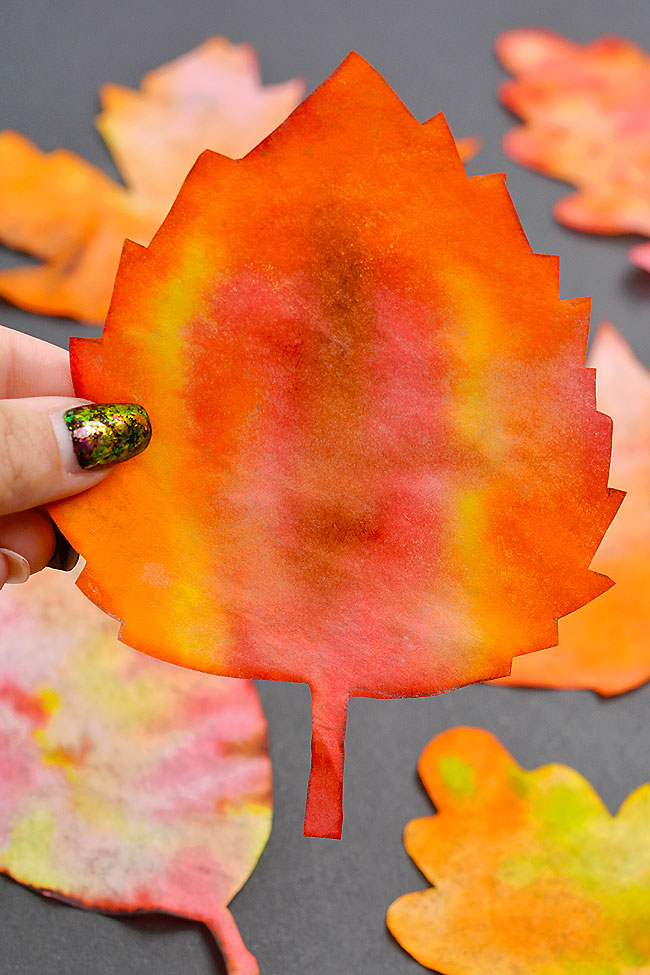 Closeup holding a red and yellow coffee filter leaf