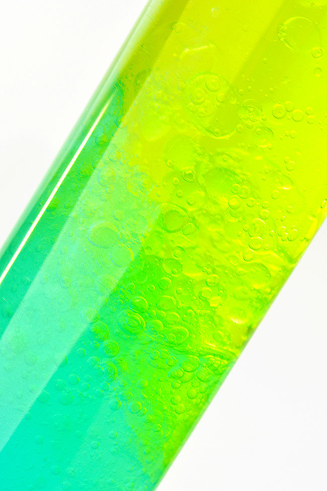 Teal and yellow color changing sensory bottle mixing to green