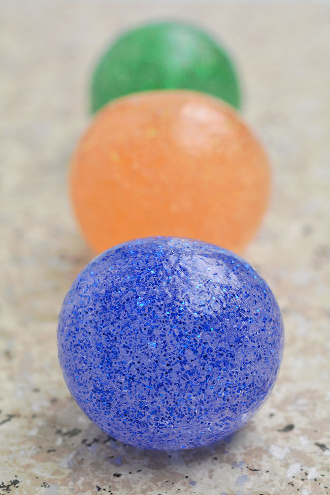 A line of blue, orange, and green glittery DIY bouncy balls