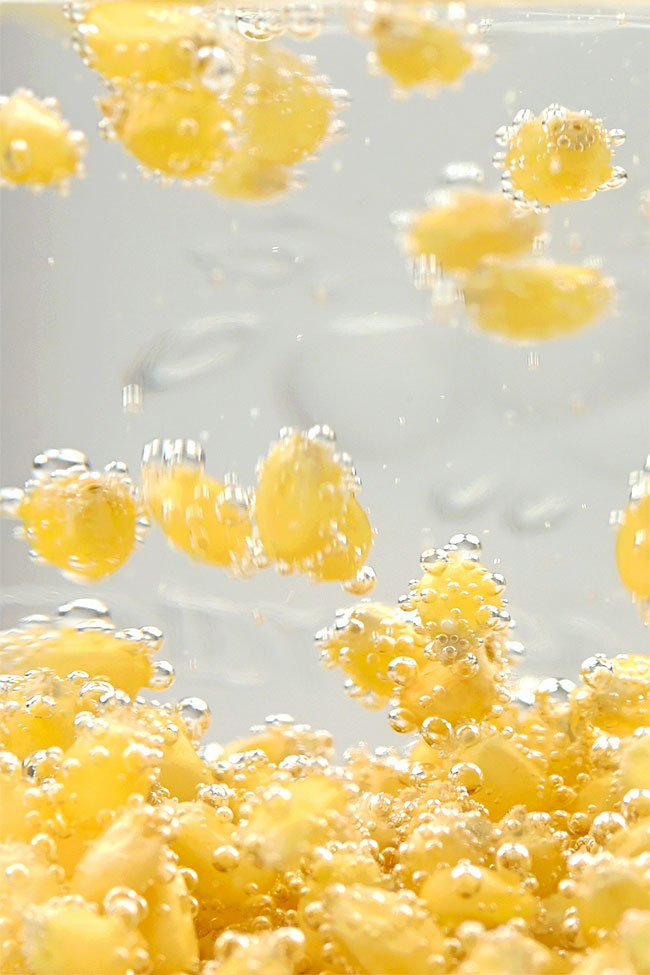 Closeup on carbon dioxide bubbles lifting the popcorn kernels in the jar