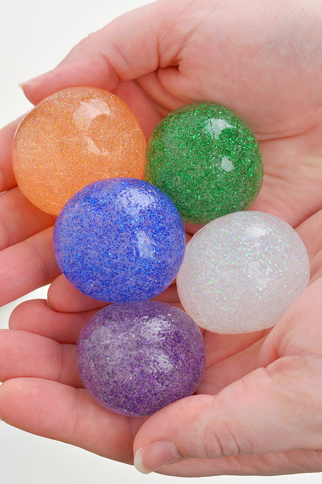 Holding DIY bouncy balls made with clear glue and glitter