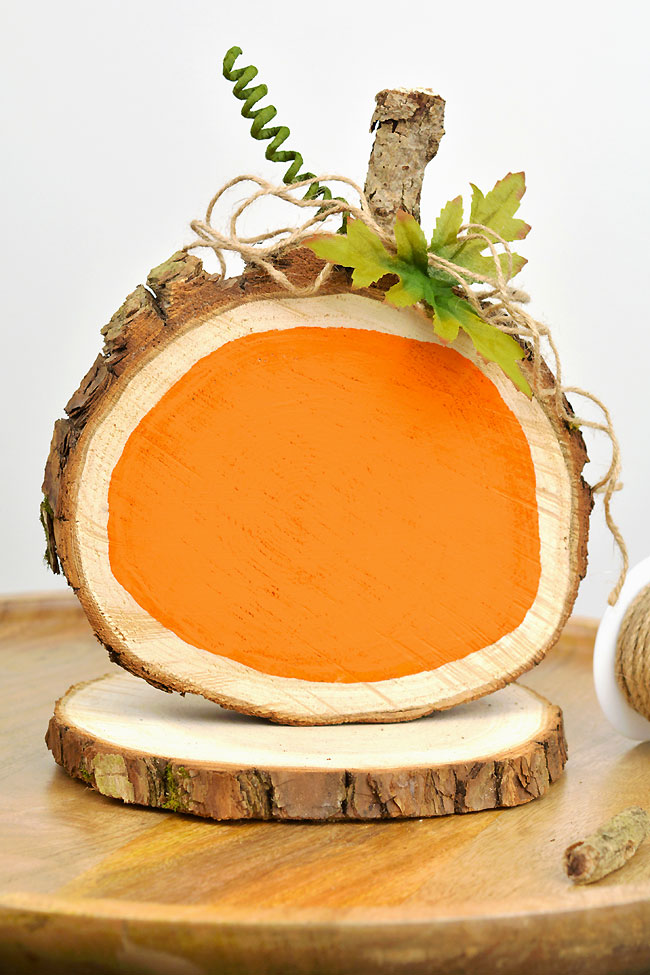 DIY pumpkin wood slice fall decoration resting on a plain wood slice