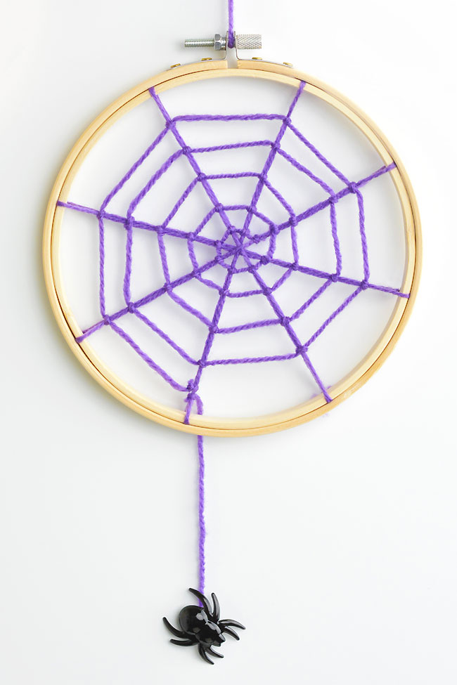 Purple yarn spider web with a spider dangling from it