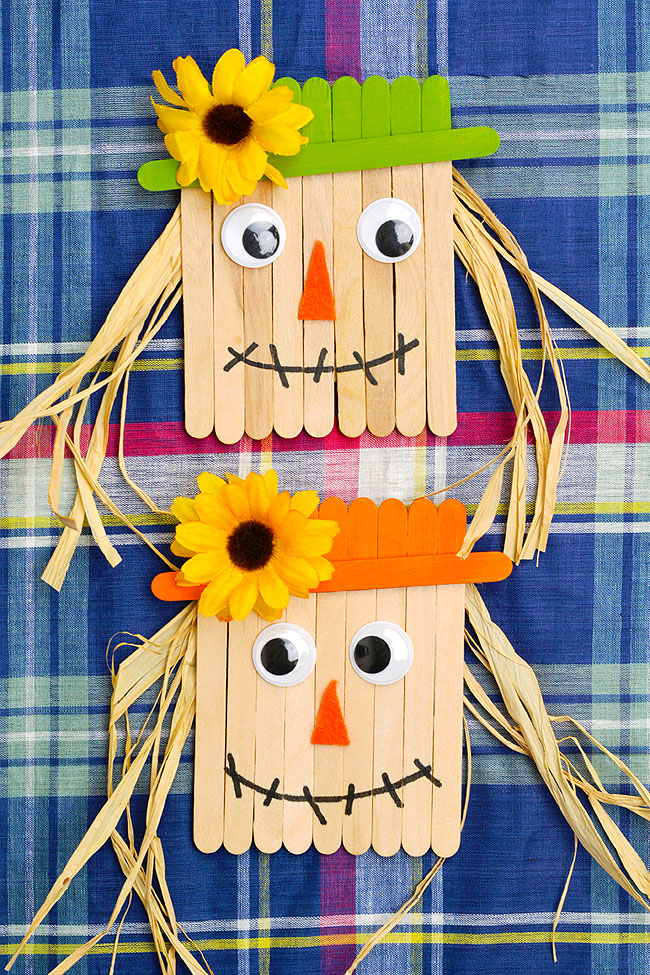 Popsicle stick scarecrows on a plaid background