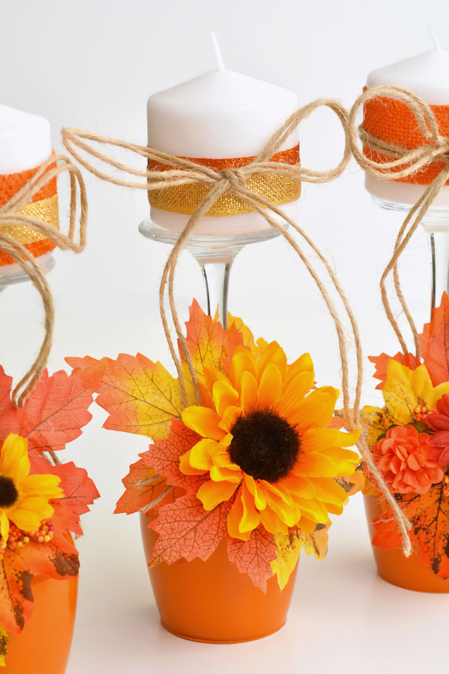 Wine glasses painted like pumpkins and decorated with fall leaves and flowers