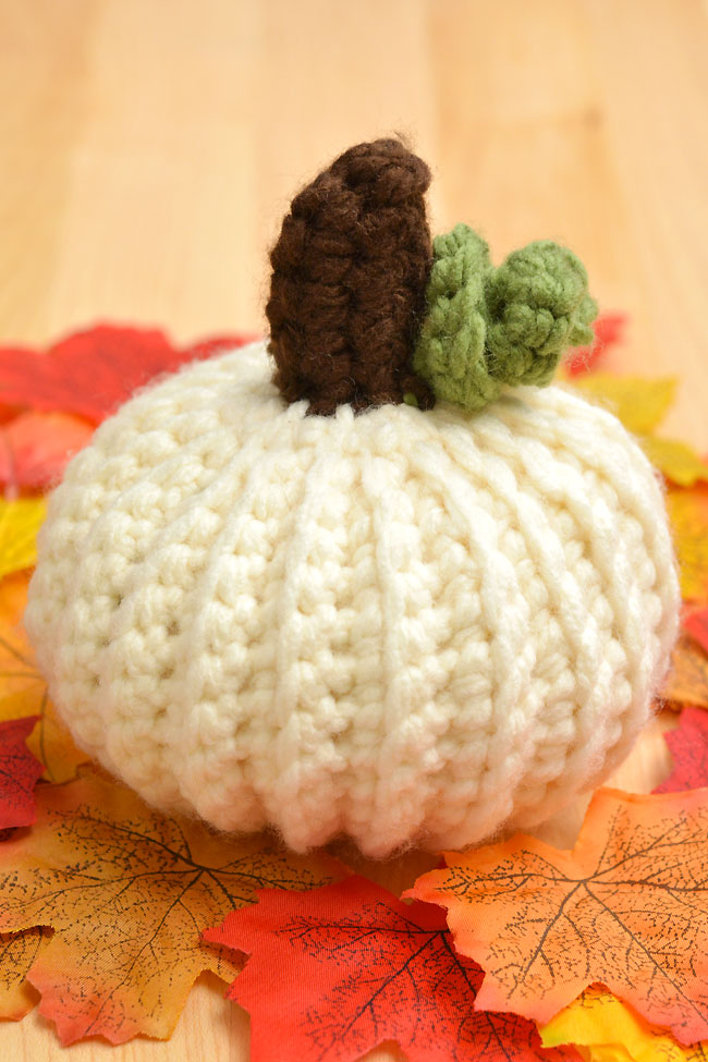 White crochet pumpkin sitting on fall leaves