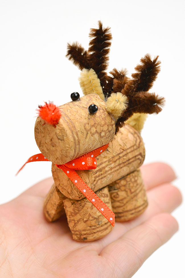 Holding a reindeer craft made from wine corks