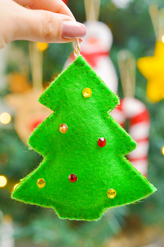 Holding a felt Christmas tree in front of a decorated Christmas tree