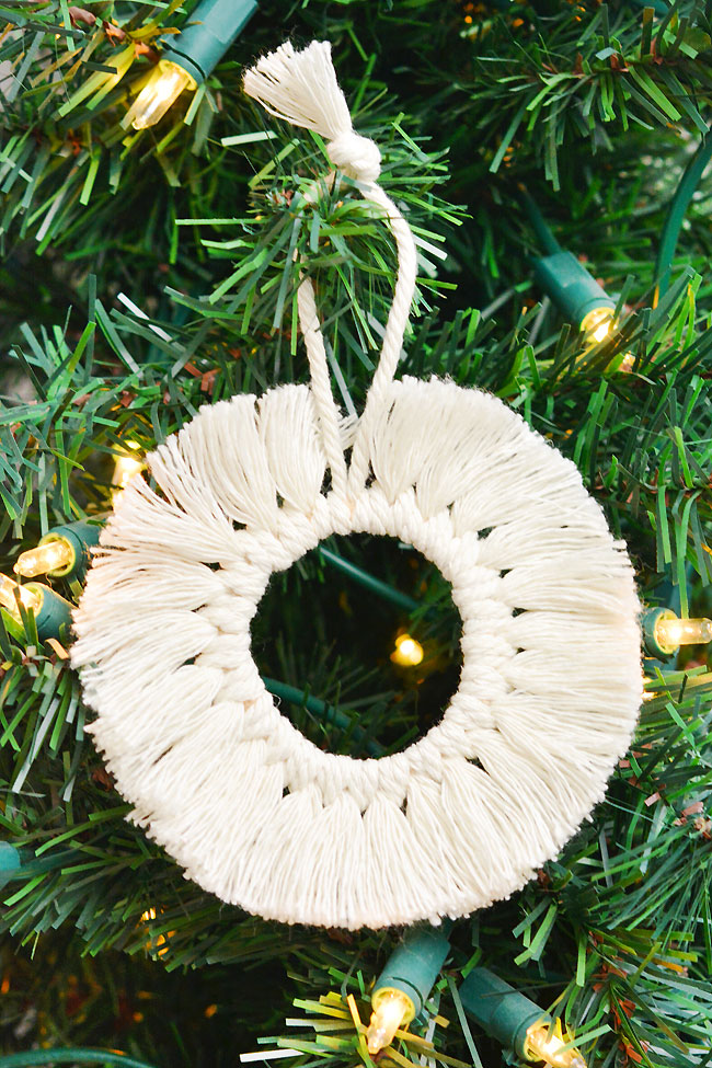 Macrame wreath ornament hanging on a lit Christmas tree