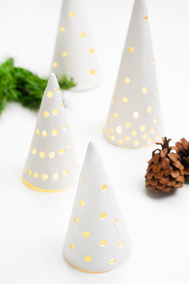 Group of white clay Christmas trees lit by battery operated candles