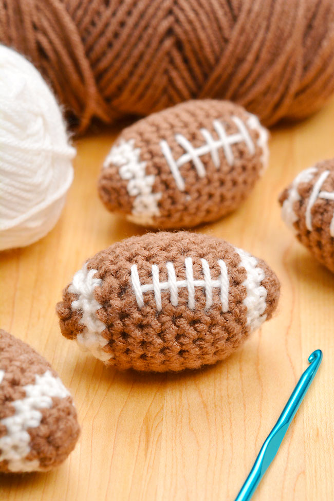Mini crochet footballs beside yarn and a crochet hook