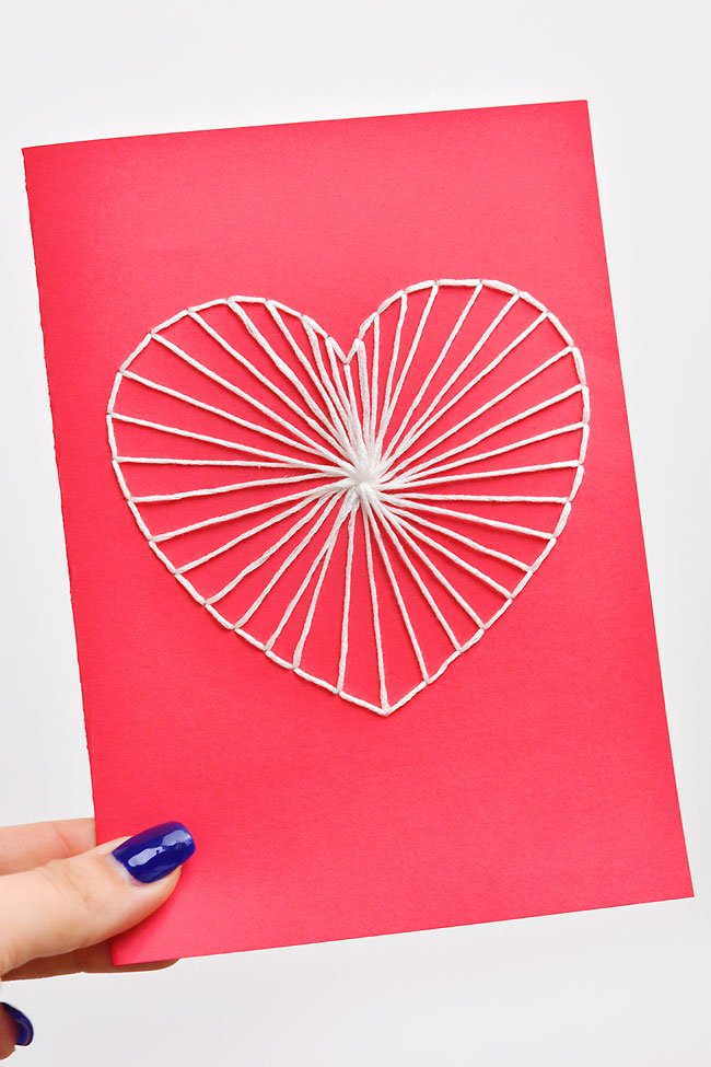 Holding a red and white DIY Valentine's Day card