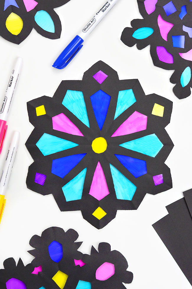 Colourful snowflake suncatcher made with black paper and markers