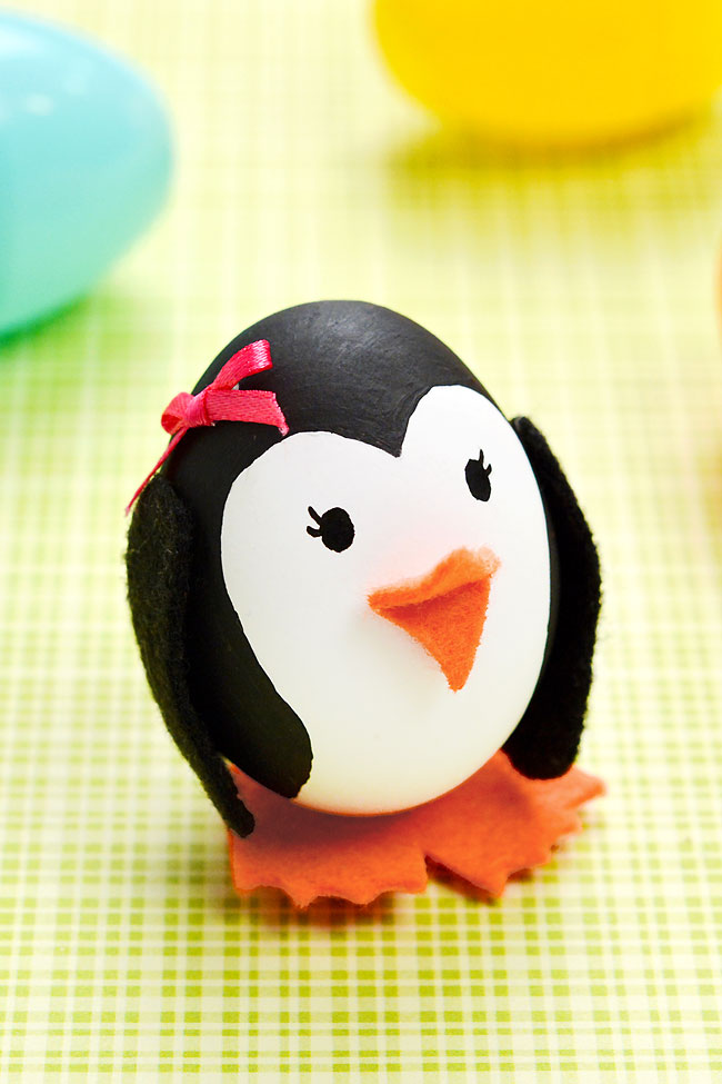 Girl Easter egg penguin on a coloured background with plastic Easter eggs