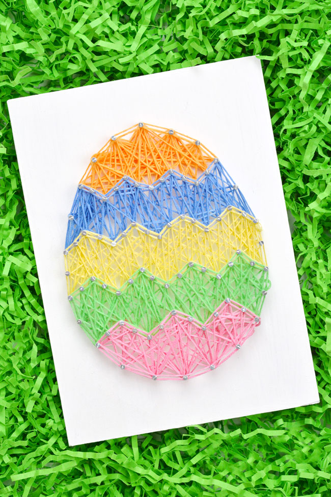 Cute and colourful Easter egg string art sitting on Easter grass