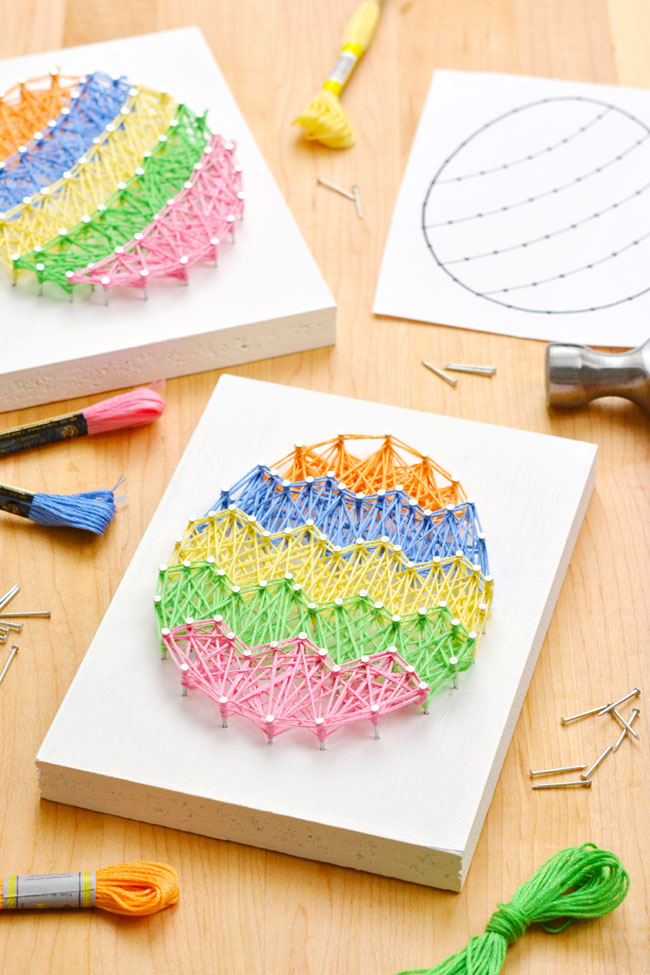 Easter string art designs on a wooden surface with supplies to make them