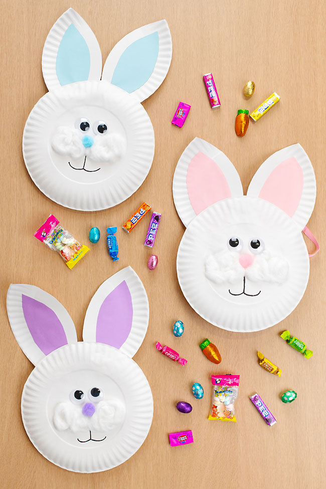 Blue, pink, and purple bunny paper plate baskets with candy around them