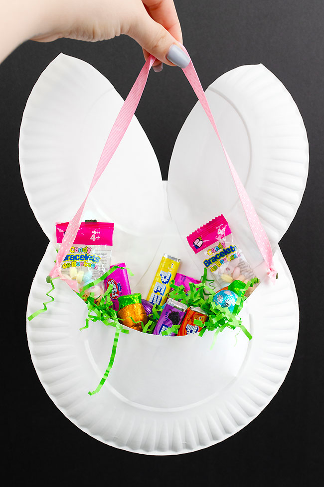 Holding a DIY Easter bunny basket filled with Easter grass and candy