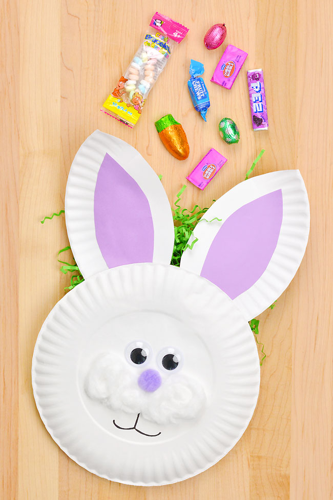 Cute paper plate bunny basket sitting with candy on a wood background