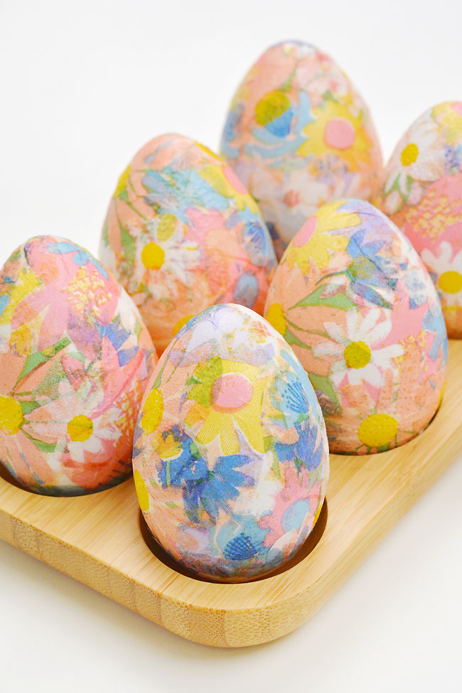 Flower print decoupage eggs sitting in a wooden egg holder