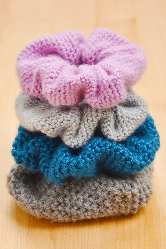 Pile of crochet scrunchies made with DK and worsted weight yarn