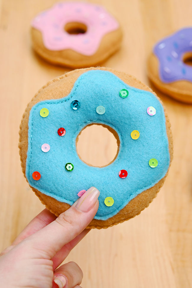 Holding a felt donut sewn together with colourful sequins as sprinkles