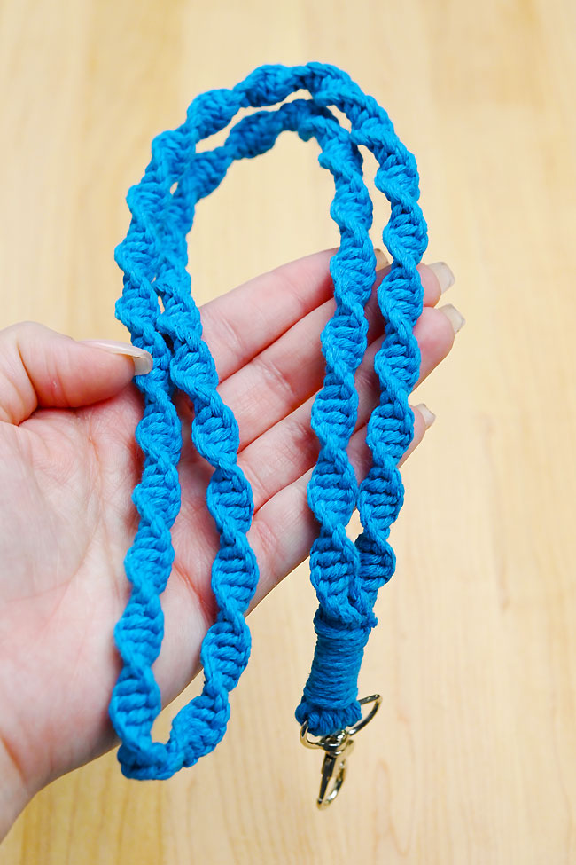 Holding a blue macrame lanyard made with spiral stitch