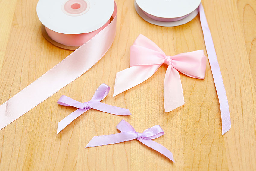 Pink and purple easy DIY bows on a wooden background