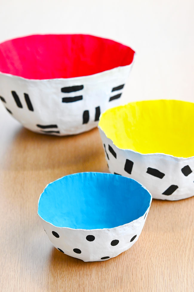 Colourful paper mache bowls on a wood background