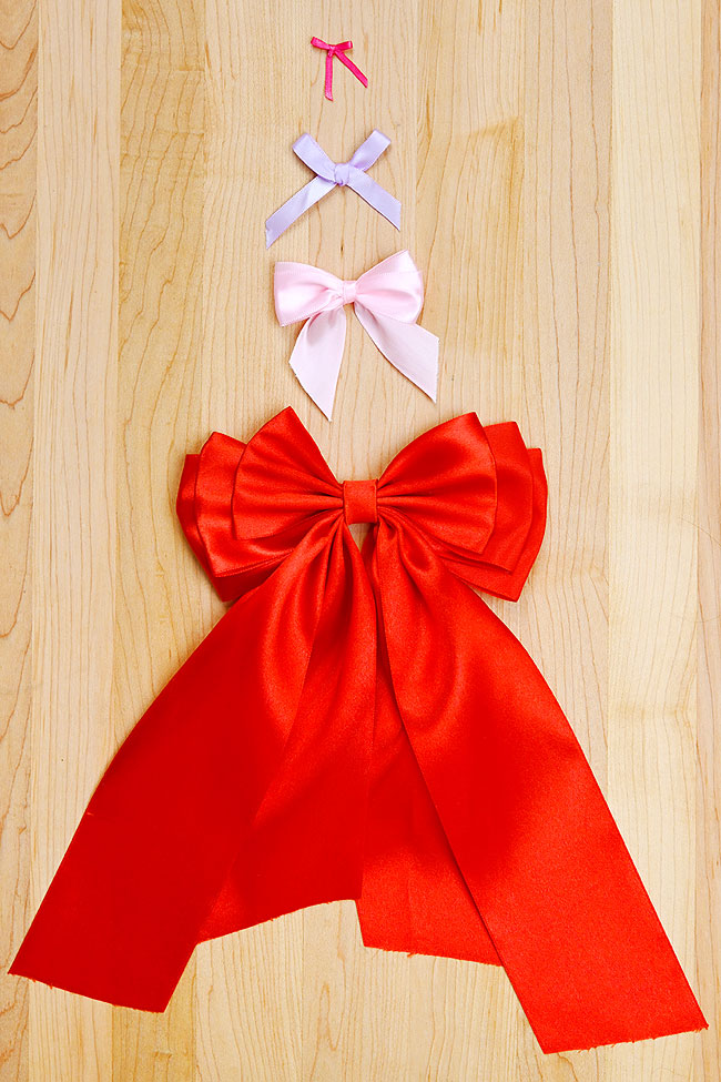 4 different styles of bows on a wooden background organized by size