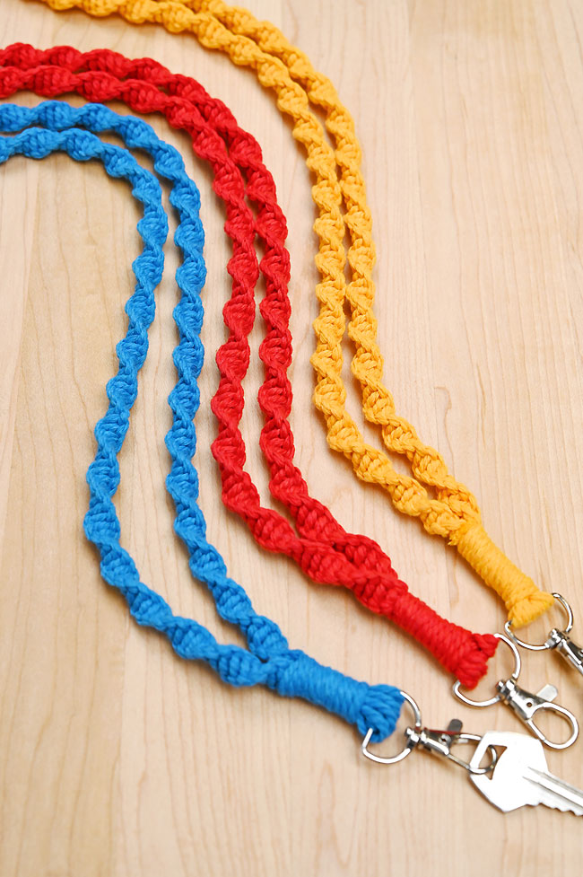 Blue, red, and yellow macrame lanyards on a wooden background