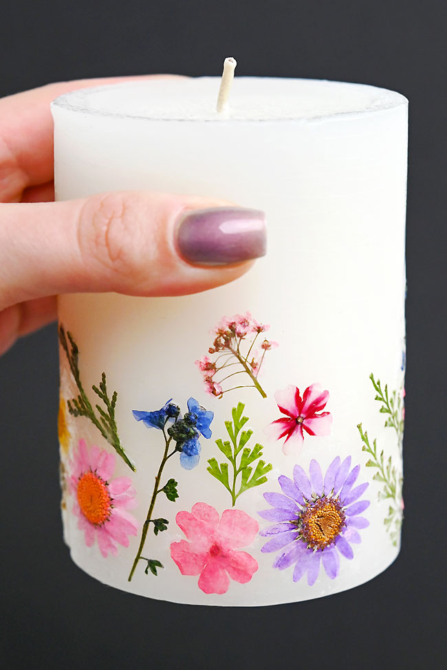 Holding a white pillar candle with pressed flowers on the side