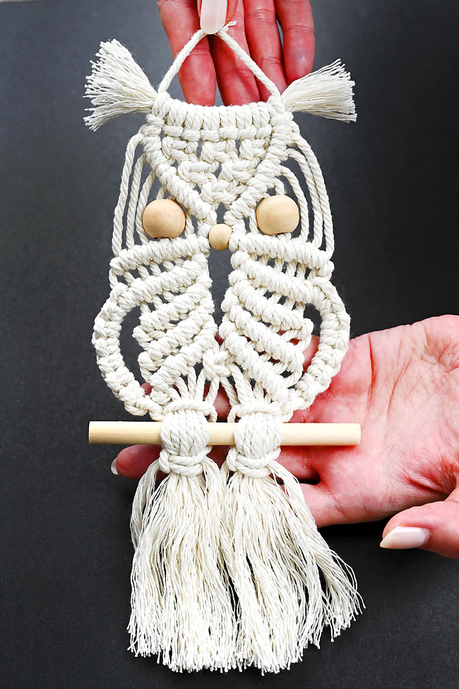 Holding a macrame owl wall hanging against a dark background