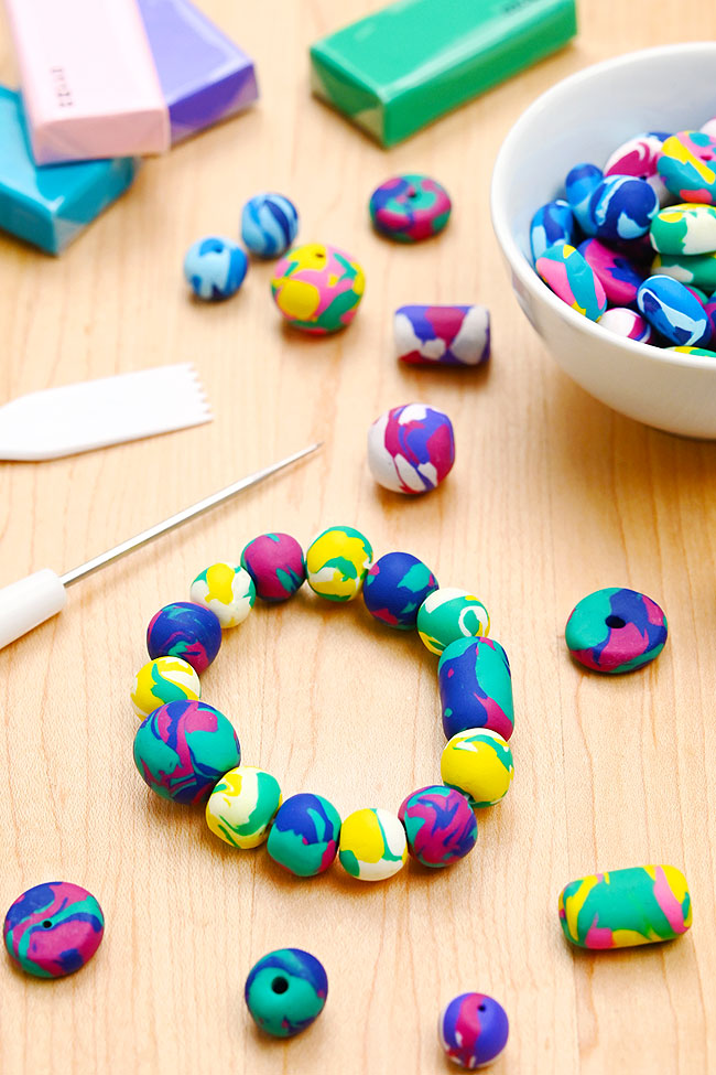 Polymer clay beads made into a bracelet with tools and clay in the background