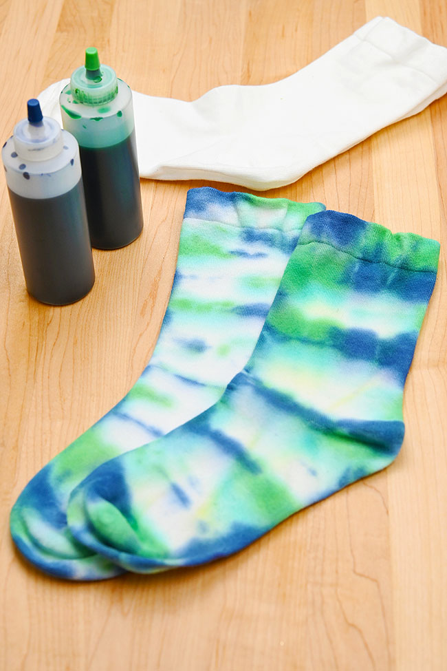 Blue and green tie dye socks with dye and white socks beside them