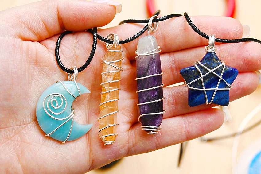 Holding three shapes of wire wrapped jewelry