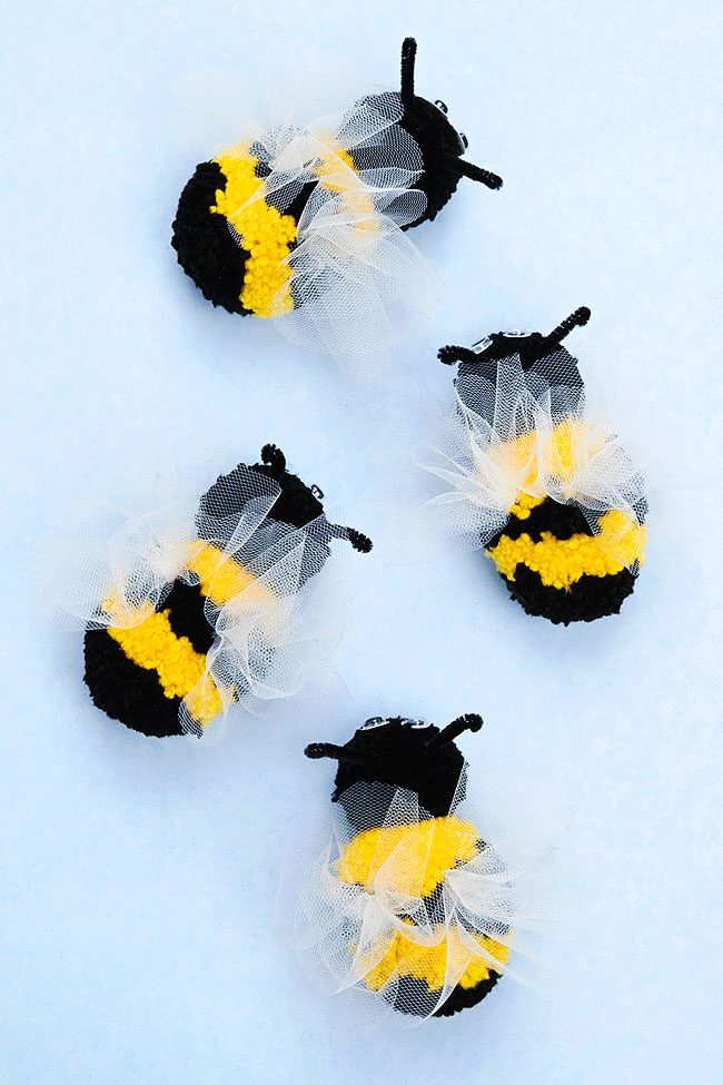 Group of bee pom poms with tulle wings on a blue background