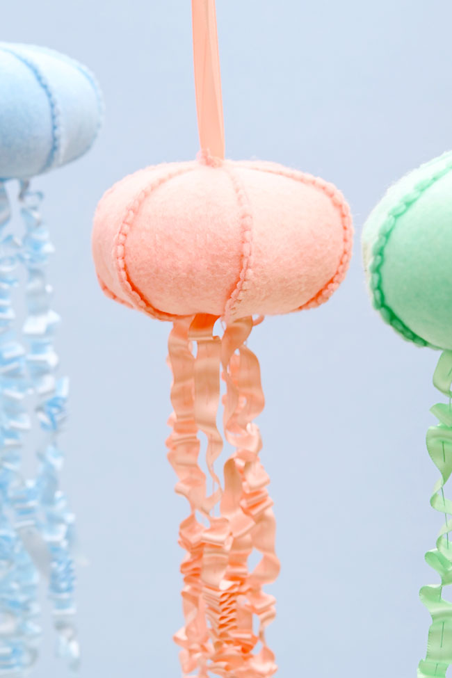 DIY felt jellyfish hanging in front of a blue background