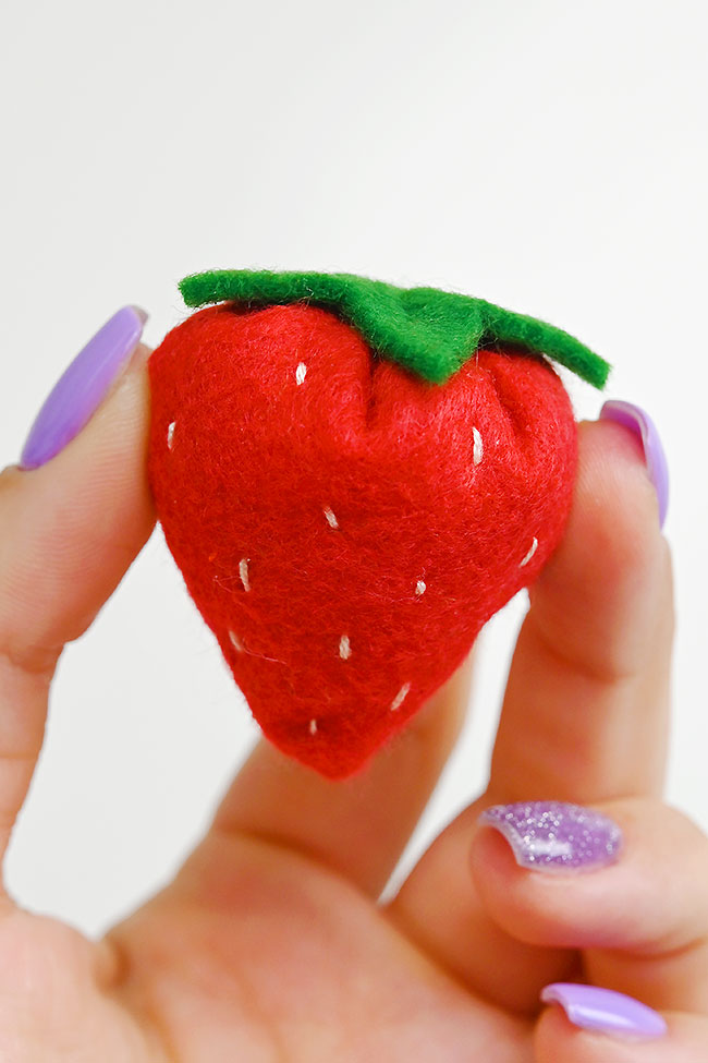 Holding a cute and soft felt strawberry