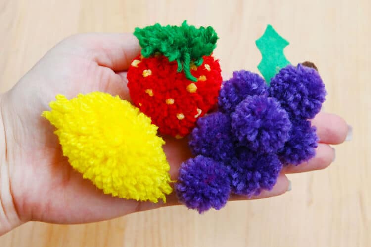 Pom Pom Fruit Holding a pom pom strawberry, lemon, and grapes