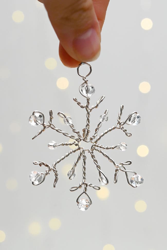 Beaded Wire Snowflake Craft Holding a beaded wire snowflake in front of fairy lights