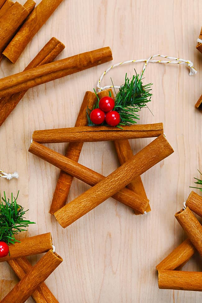 Cinnamon Stick Star Pattern Closeup on a cinnamon stick star with 3 holly berries and Christmas greenery