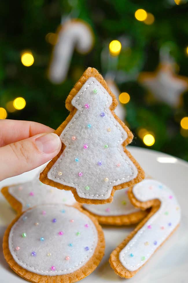 Felt Sugar Cookies Holding a Christmas tree shaped felt cookie above a plate of felt food
