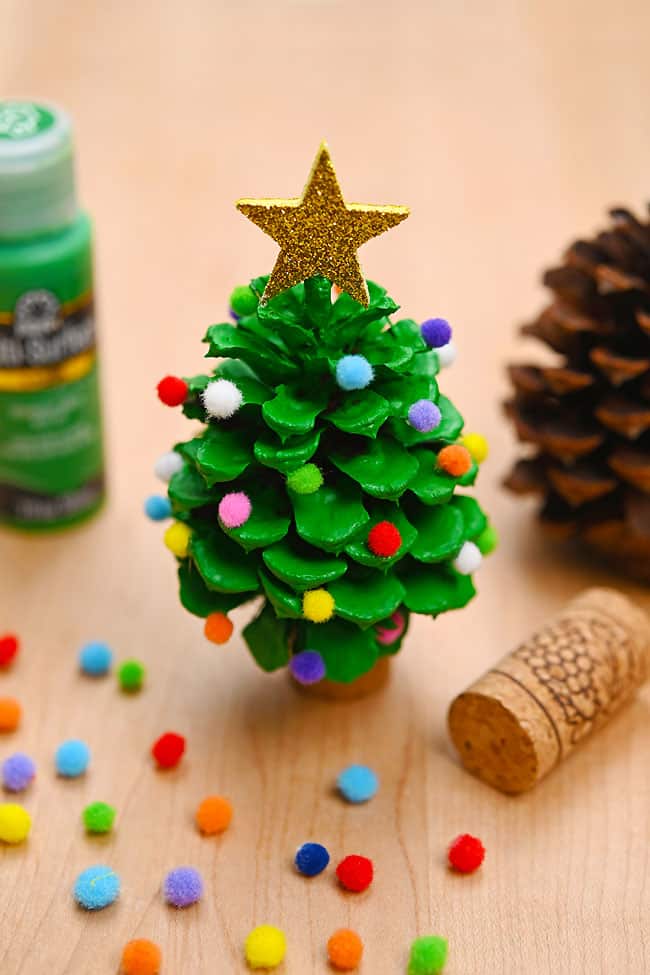 Closeup on a pine cone Christmas tree beside craft supplies to make one