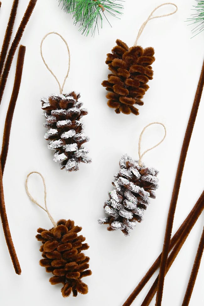 Pipe Cleaner Pine Cone Ornament Pinecone pipe cleaner ornaments sitting on a white background with supplies to make them